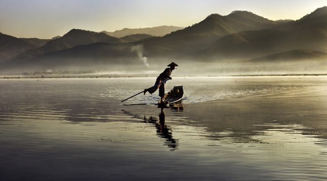 Steve McCurry, fisherman paddles his boat along Inle Lake